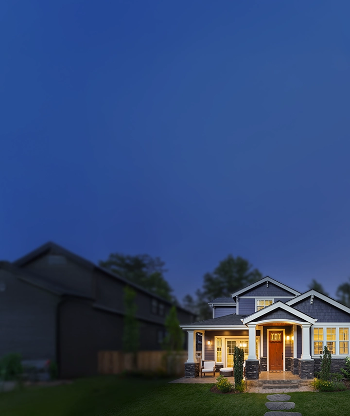 A house in the suburbs with lights on at dusk